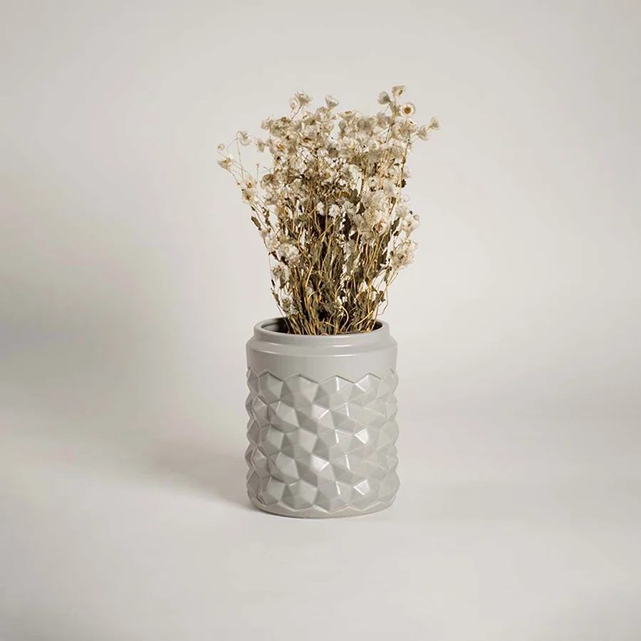 Modern grey ceramic vase with geometric texture displayed in a lifestyle setting enhancing the decor with a subtle contemporary touch.