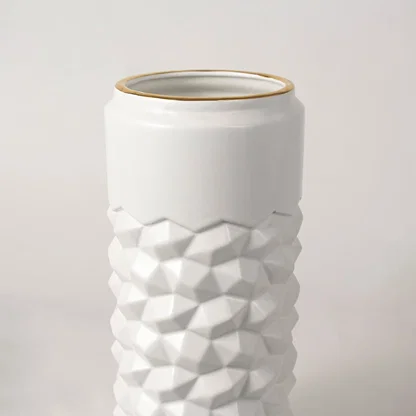 White ceramic decorative vase with geometric texture and gold rim for shelf styling and modern home decor displays.