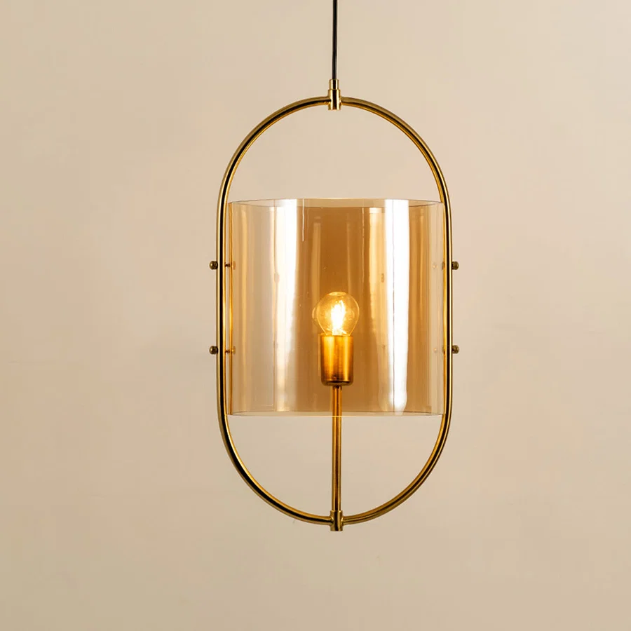 Elegant gold metal pendant light with amber glass shade for stylish dining room and kitchen decor styling.