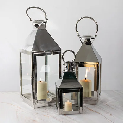 Black metal lantern candle holders with clear glass panels styled for modern dining table and home decor use.