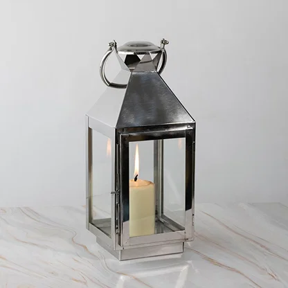 Stainless steel lantern lit displayed plain on white background highlighting polished finish.
