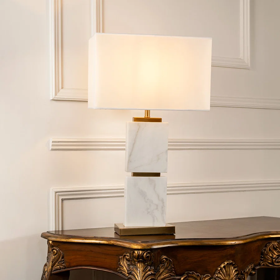 Teal glass table lamp with fabric shade displayed on a wooden console table creating elegant ambient lighting indoors.