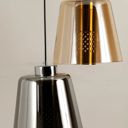 Amber gold and smoke glass pendant lights illuminated to highlight premium craftsmanship and contemporary lighting design.