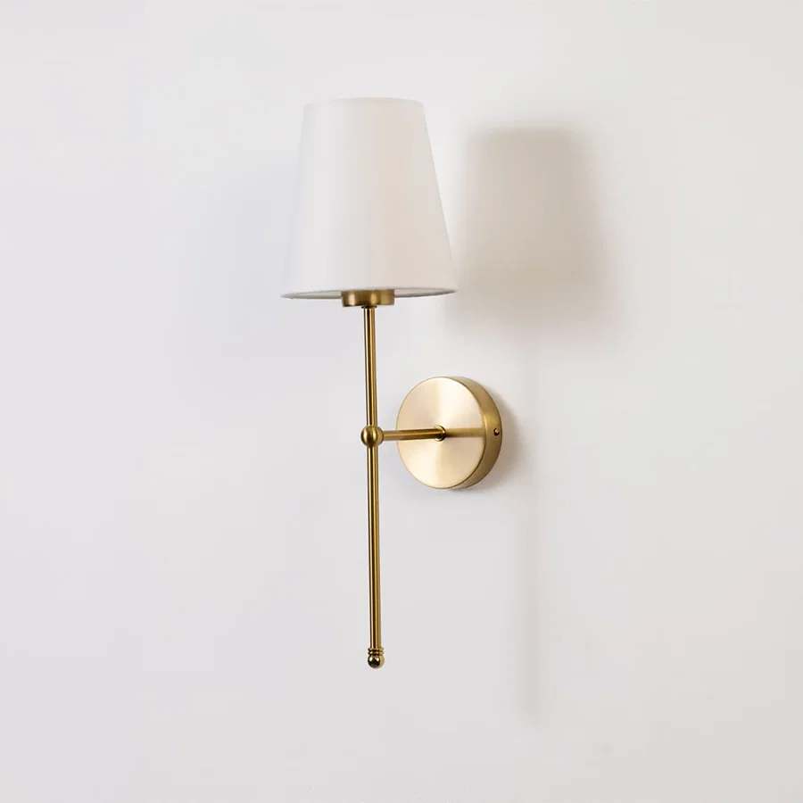 Gold wall light with a white shade displayed on a white background showing its elegant minimal shape.