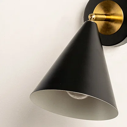 Closeup of black metal wall light with cone shade and gold mount showcasing smooth finish for modern interior decor styling.