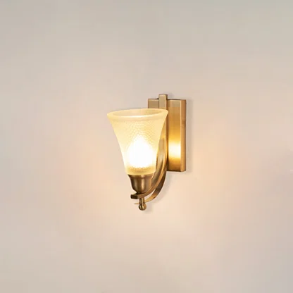 Illuminated brass wall sconce with glowing frosted glass shade and curved arm design on clean white background display.