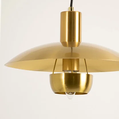 Gold metal pendant light illuminated to display luxury ceiling lighting with elegant modern decorative styling.