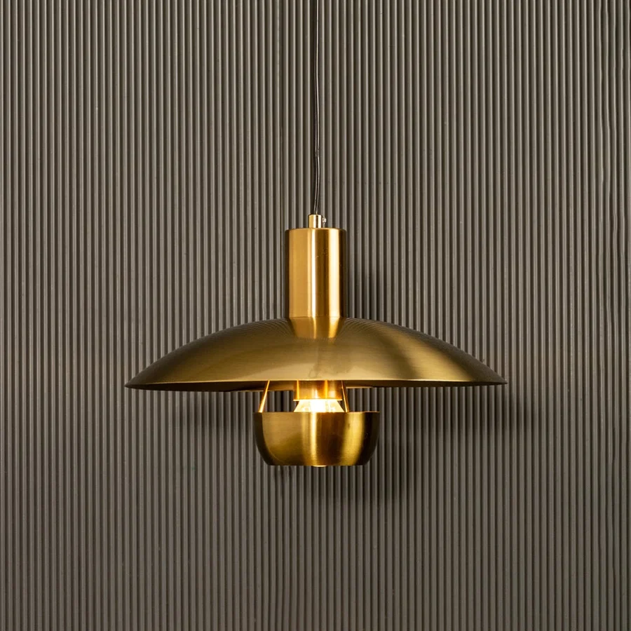 Golden metal pendant light shining warmly on dark background accentuating its smooth curves and contemporary luxe appeal.