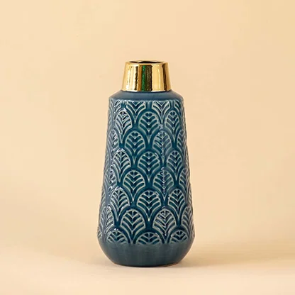 Detailed view of blue ceramic vase showing intricate leaf pattern with reflective gold neck and smooth glaze.