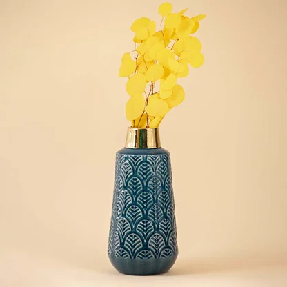Elegant blue ceramic vase with gold detailing and textured pattern highlighted under soft neutral lighting.