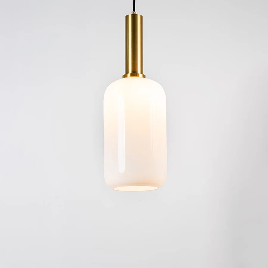 White glass pendant light with brass metal holder and minimalist cylindrical design for elegant ceiling lighting decor.