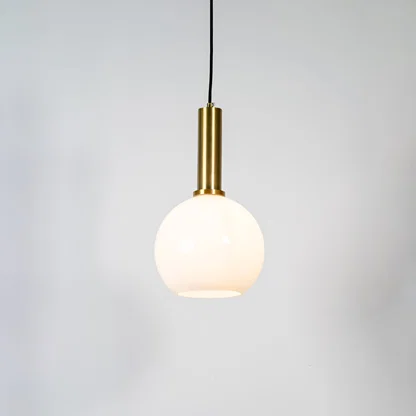 White glass globe pendant light with brass metal holder and minimalist design for contemporary ceiling lighting decor.