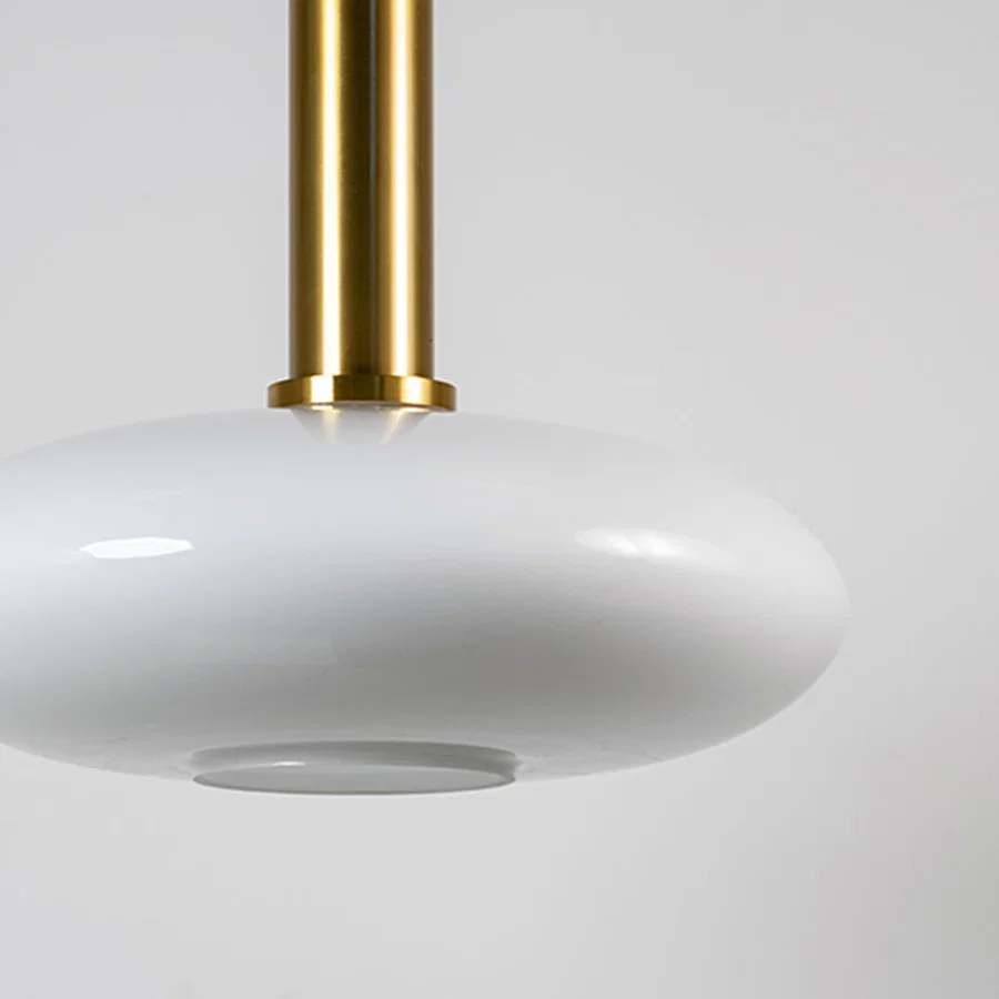 White glass pendant light with brass metal fixture showcasing smooth glossy finish and refined modern lighting style.