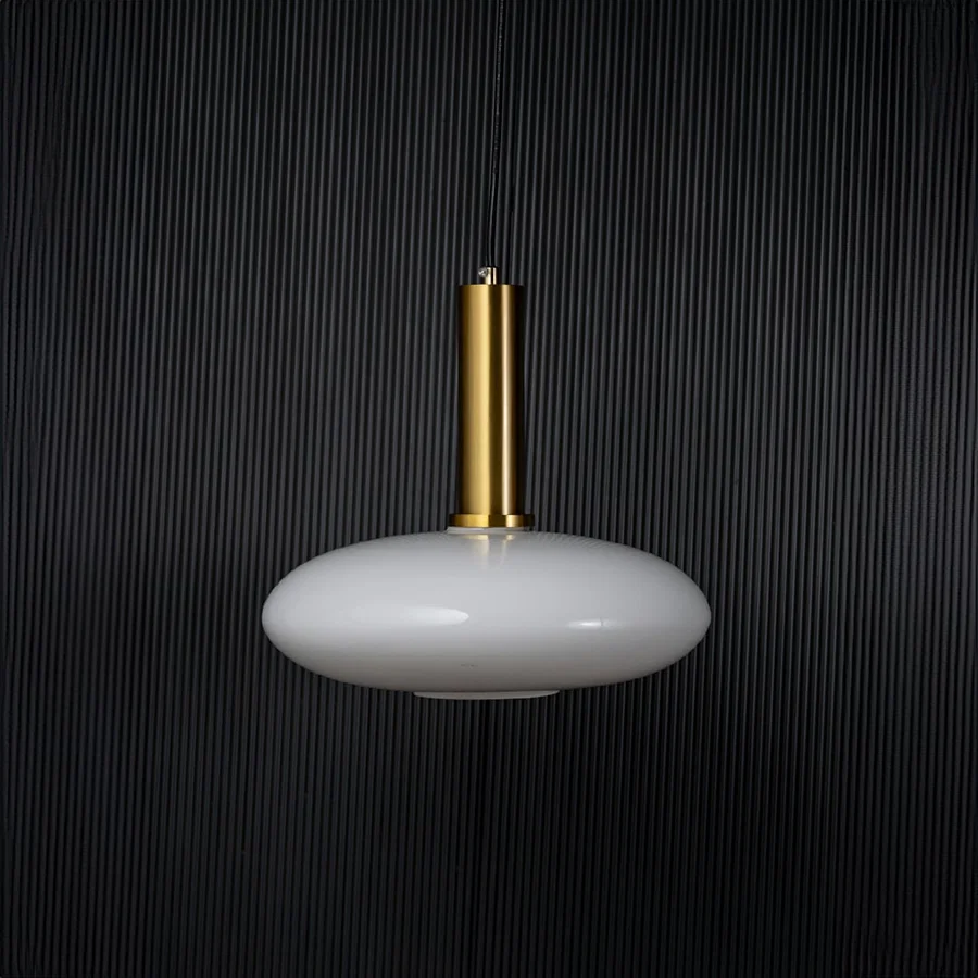 Disc pendant light turned off with brass accent and glass shade displayed as modern ceiling decor on black background.