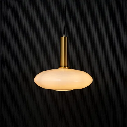 Elegant disc pendant light turned on with warm glow creating ambient ceiling decor on black background.