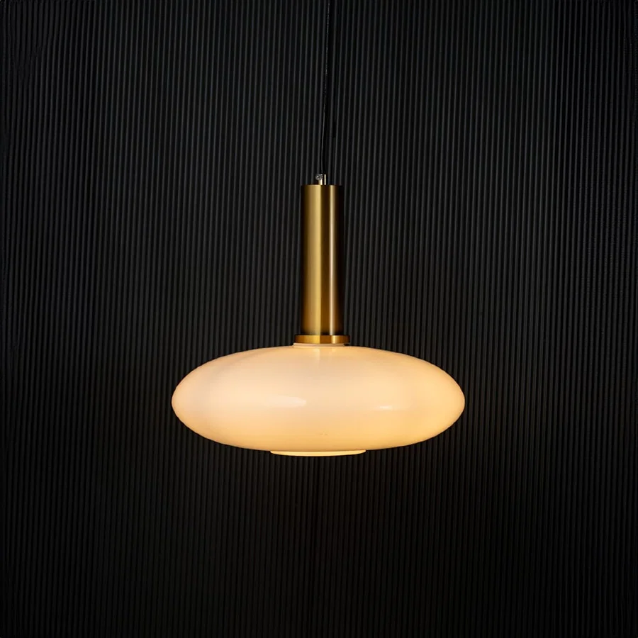 Elegant disc pendant light turned on with warm glow creating ambient ceiling decor on black background.
