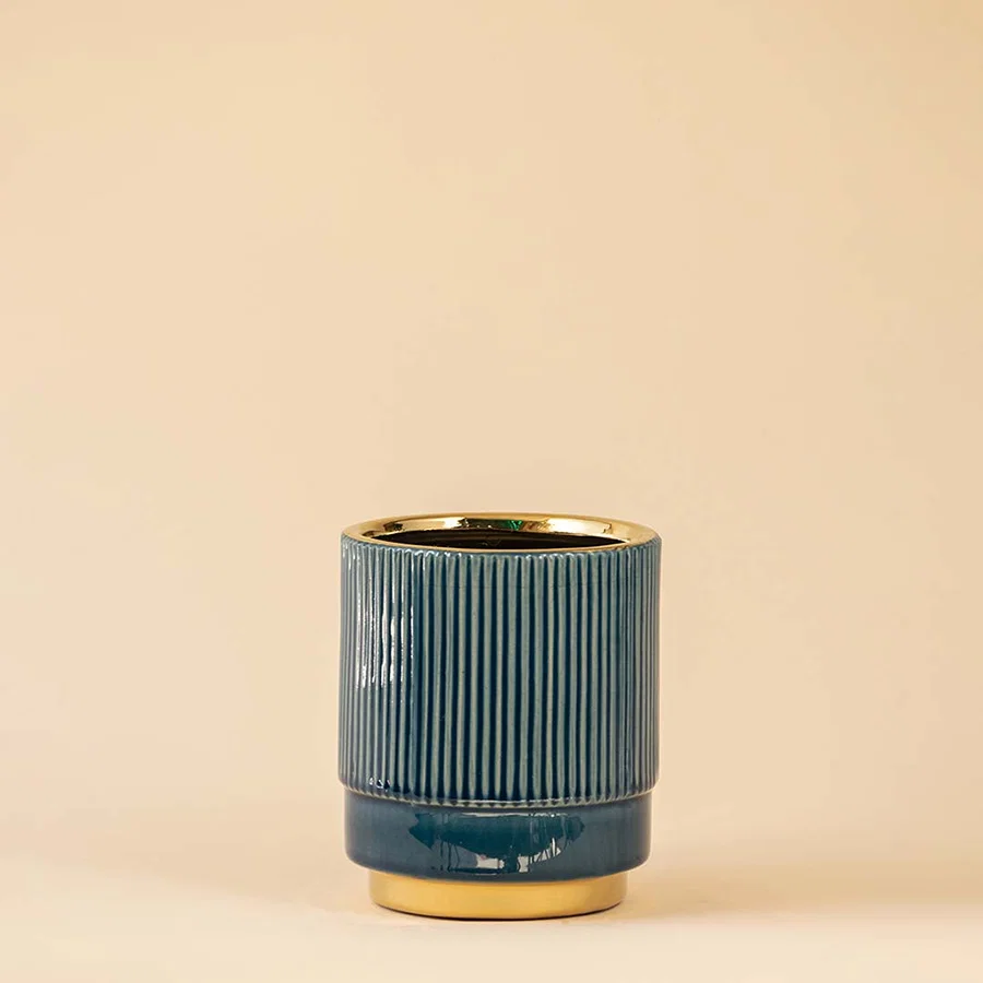 Blue ceramic decorative vase with fluted texture and gold rim for sophisticated shelf styling and home decor.