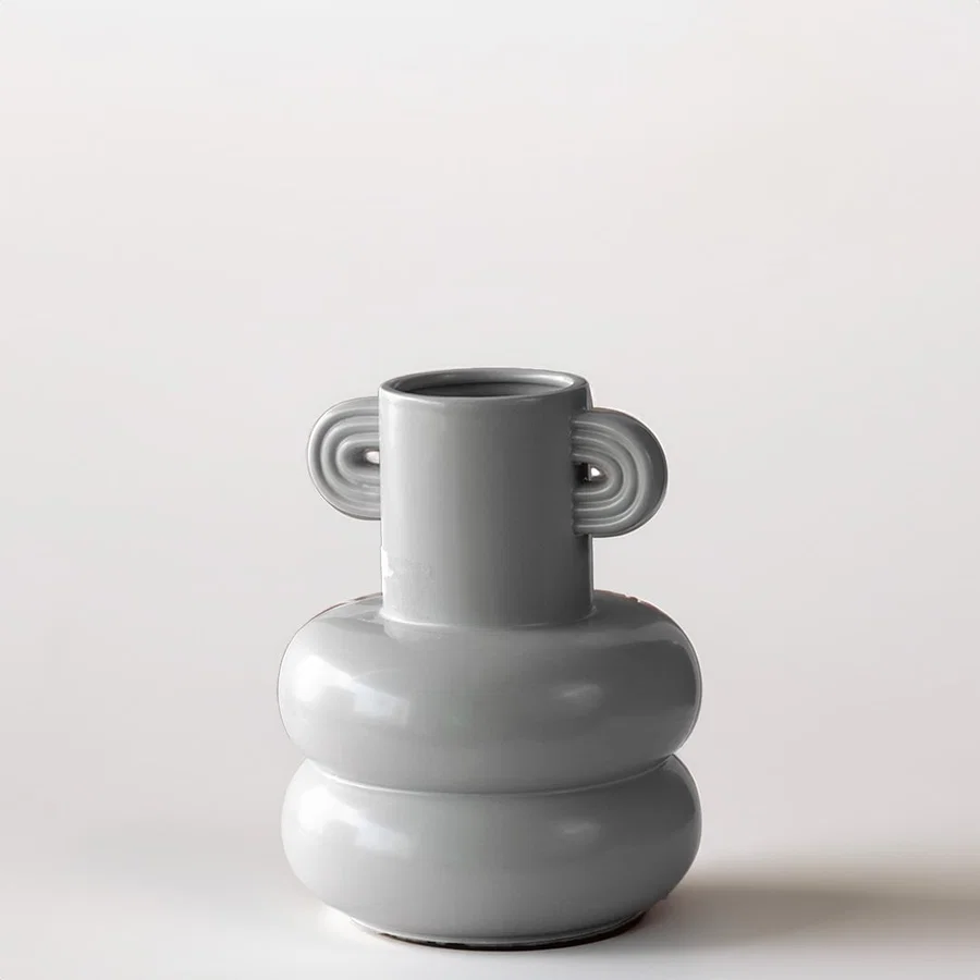 Grey sculptural vase placed on a marble surface with a warm brown backdrop creating a soft lifestyle scene.