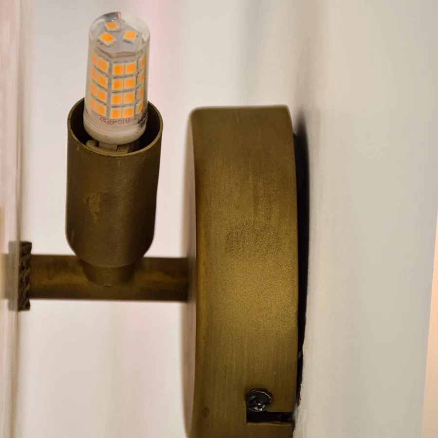Closeup of gold metal wall light with marble finish for elegant hallway and luxury decor styling spaces.