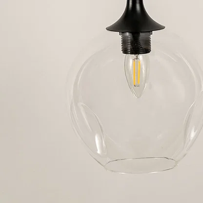 Closeup of clear glass pendant light with black metal top showcasing elegant craftsmanship and refined style.