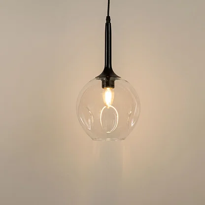 Clear glass pendant light with black holder and visible filament bulb modern minimal lighting for kitchen and dining decor.

