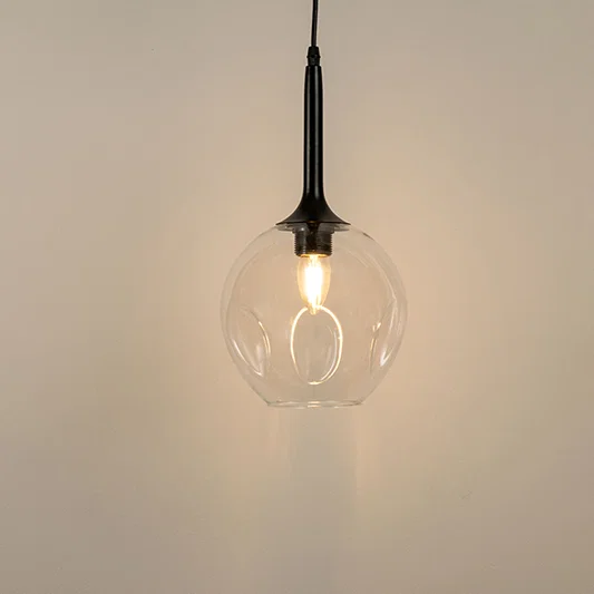 Clear glass pendant light with black holder and visible filament bulb modern minimal lighting for kitchen and dining decor.


