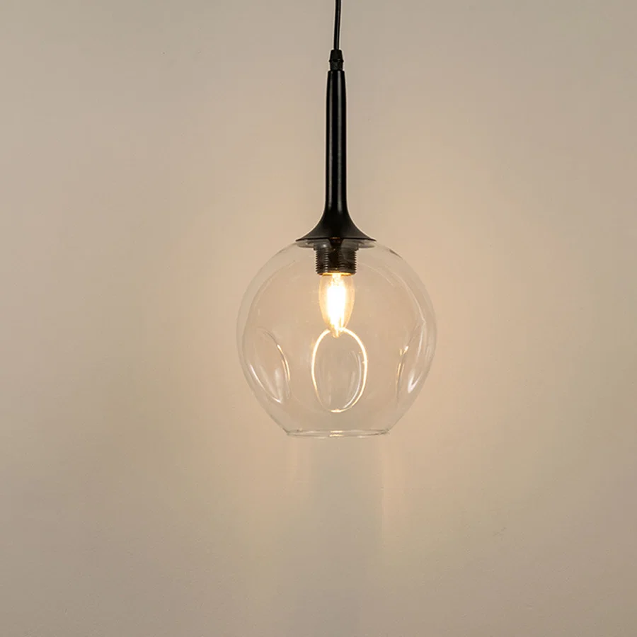 Clear glass pendant light with black holder and visible filament bulb modern minimal lighting for kitchen and dining decor.

