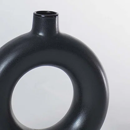 A closeup view of the black circular vase focusing on its smooth matte texture and perfectly rounded hollow center for a refined modern decor finish.