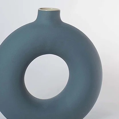 Closeup of matte green ceramic donut vase with smooth round hollow design modern centerpiece for living room decoration.