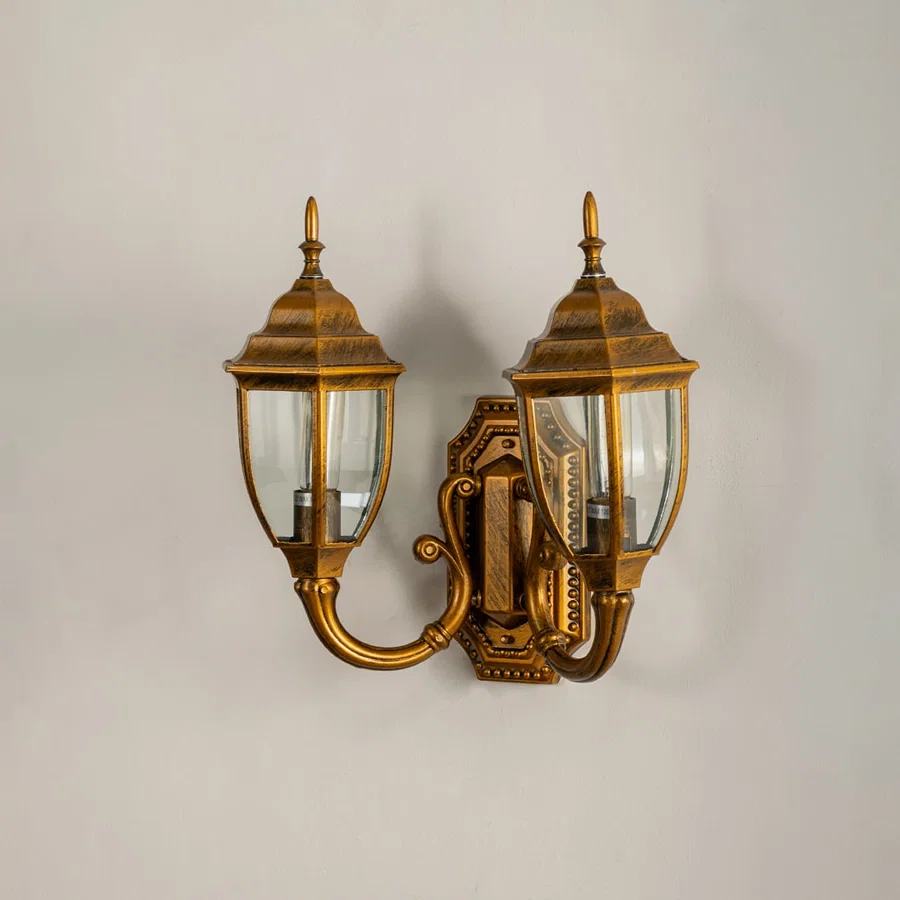 Antique brass double outdoor lantern on white background with lights off showing elegant curved design clear glass panels and decorative metal detailing.