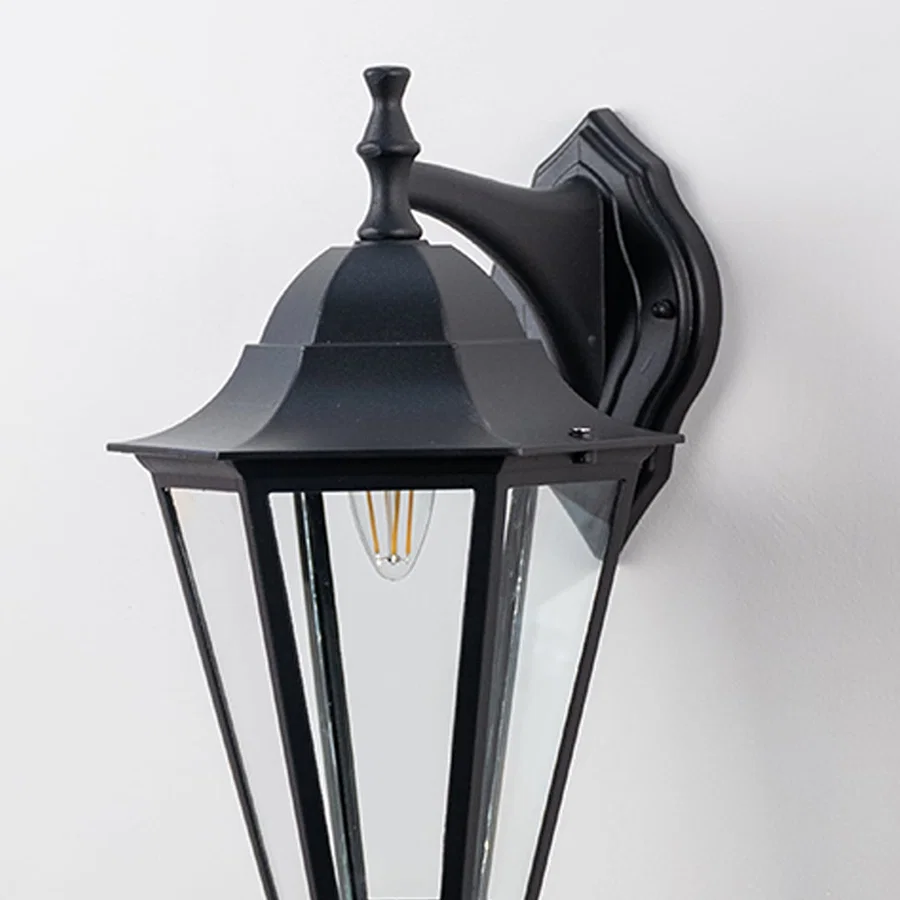 Closeup of decorative outdoor wall lantern with sleek black metal frame and clear glass panels showcasing bulb design.