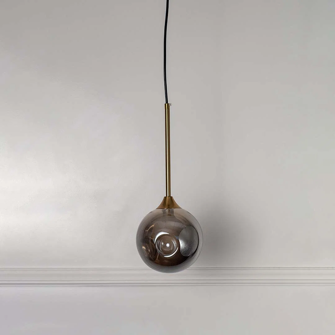 Reflective smoky glass pendant light with brass fittings designed for stylish contemporary spaces.