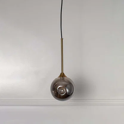 Reflective smoky glass pendant light with brass fittings designed for stylish contemporary spaces.