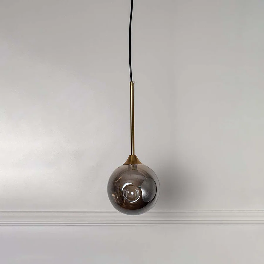Reflective smoky glass pendant light with brass fittings designed for stylish contemporary spaces.