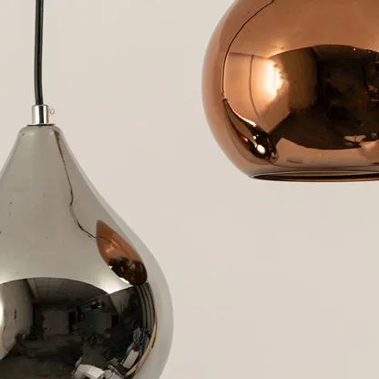 Silver and copper metal pendant lights closeup highlighting mirrored finishes and luxury lighting craftsmanship quality.