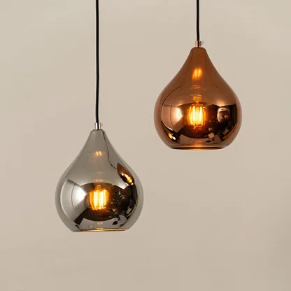 Silver and copper metal pendant lights illuminated to showcase elegant modern ceiling lighting with reflective styling.