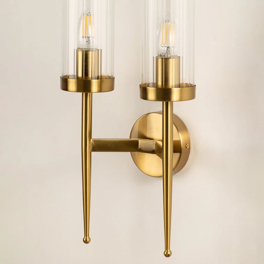 Closeup view of the double glass wall light displaying the transparent cylindrical shade and warm glowing filament bulb through the detailed glass.