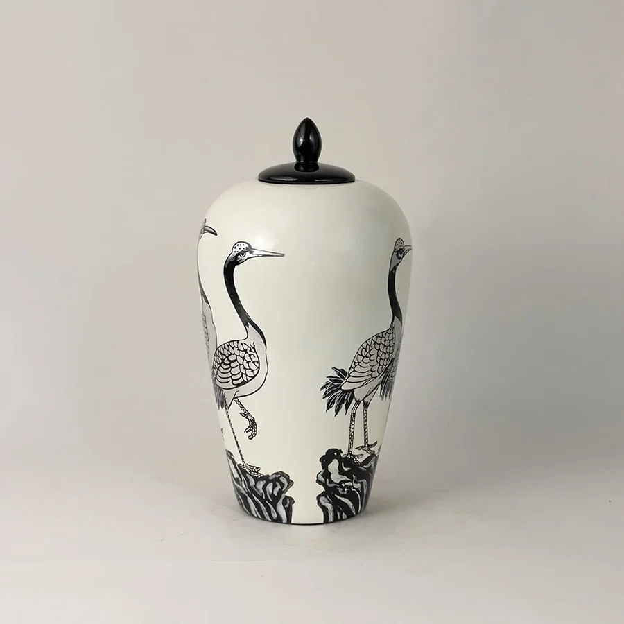 Side view of white ceramic jar with hand-painted crane pattern and black lid highlighting intricate artistic detailing.