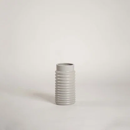Modern light grey ceramic vase with ribbed design displayed on a white background ideal for minimalist decor and tabletop styling.