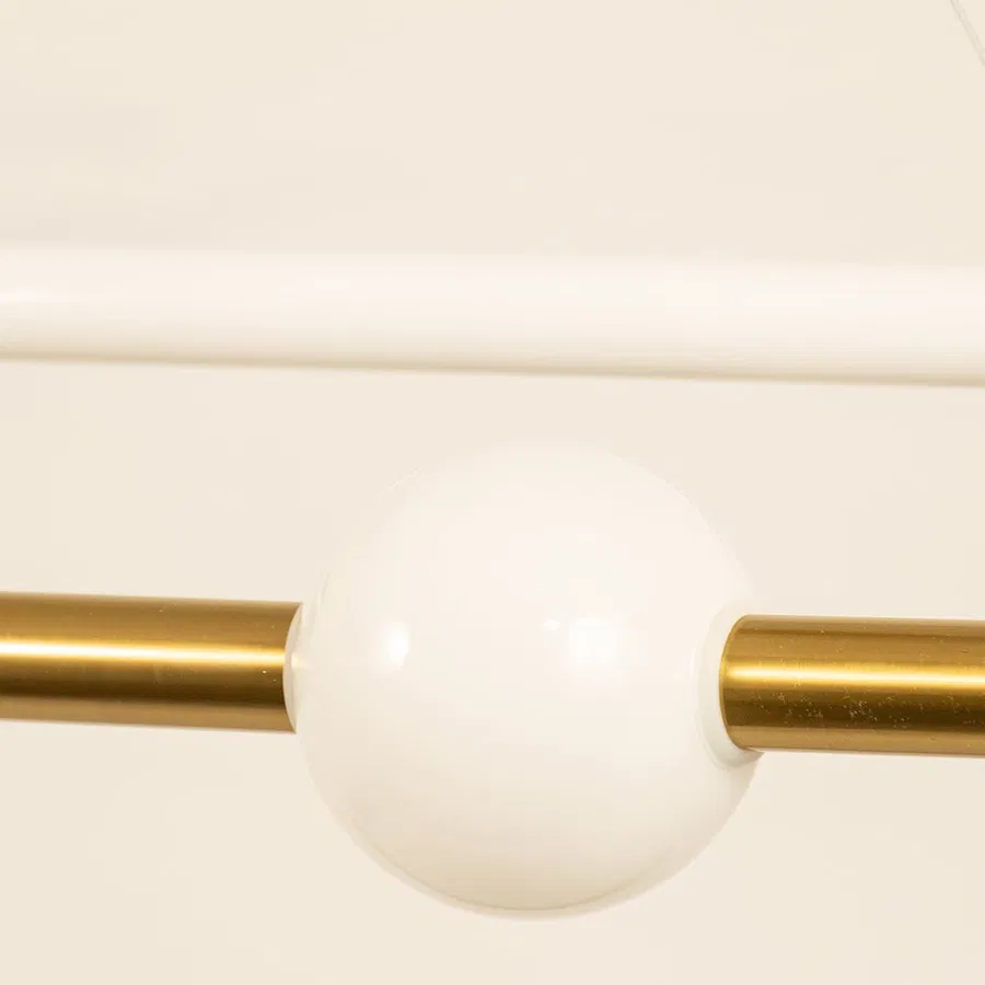 Gold metal linear pendant light closeup featuring frosted globe detail and premium modern lighting design.