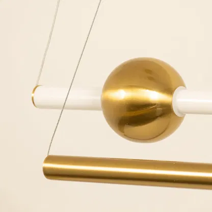 Gold metal linear pendant light closeup highlighting brushed finish and contemporary decorative lighting craftsmanship.