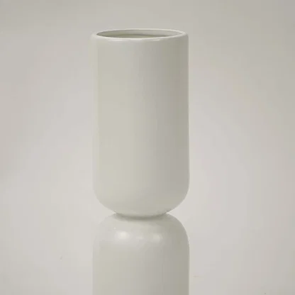 Closeup image of a minimalist matte white ceramic totem vase showing its smooth stacked pill shape and seamless joints.