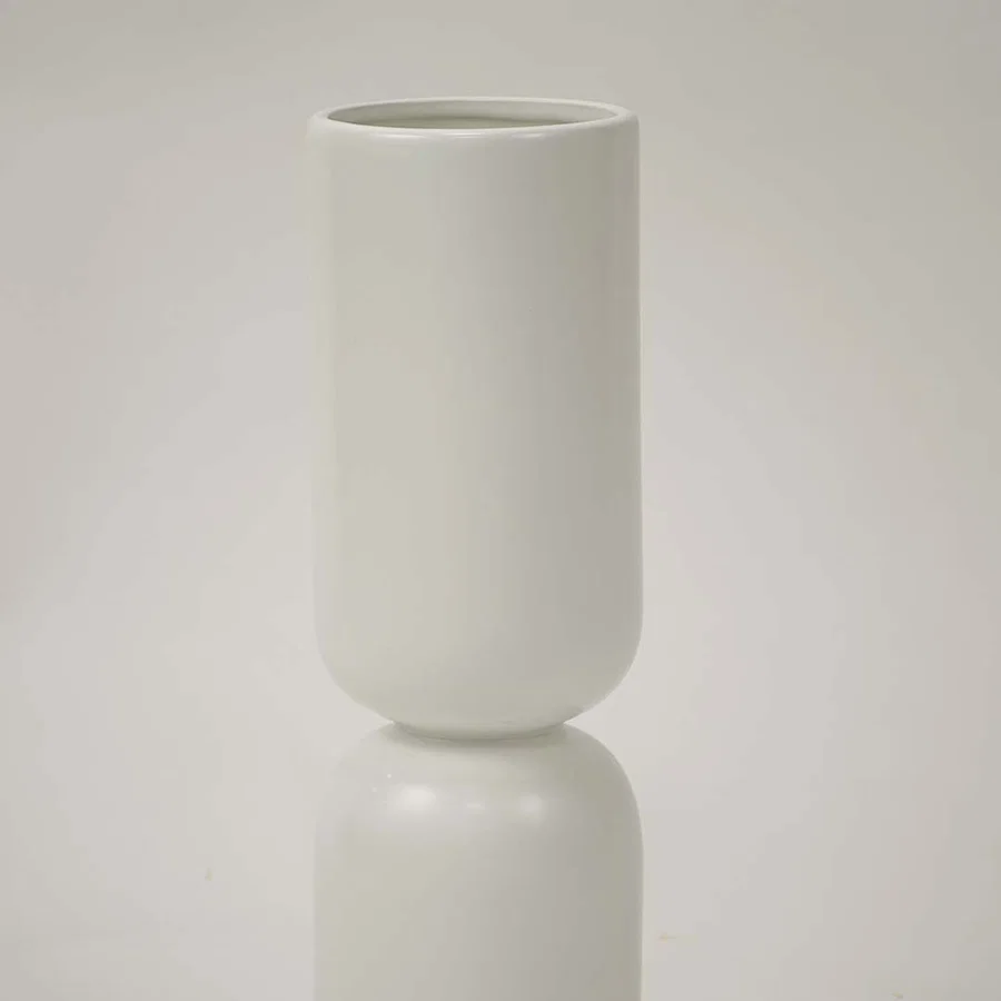 Closeup image of a minimalist matte white ceramic totem vase showing its smooth stacked pill shape and seamless joints.