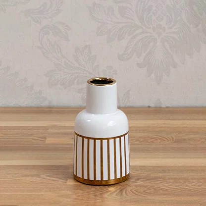 White ceramic vase with gold ribbed detailing styled on a wooden table for elegant contemporary home decor.