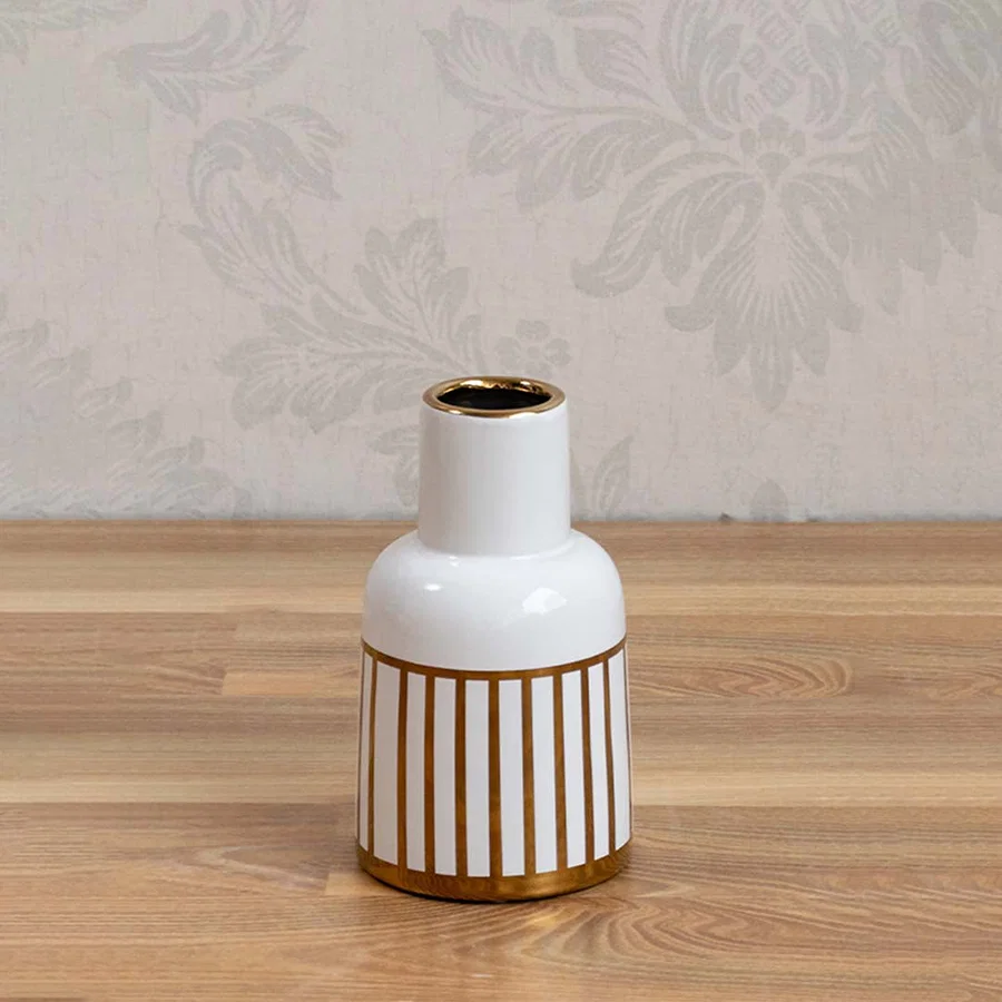 White ceramic vase with gold ribbed detailing styled on a wooden table for elegant contemporary home decor.
