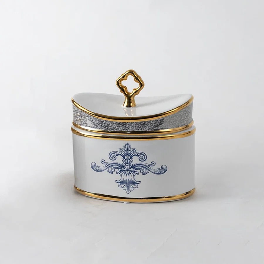 White ceramic jar with gold lid and blue artwork in a front view ideal for luxury décor styling and premium tabletop accents.