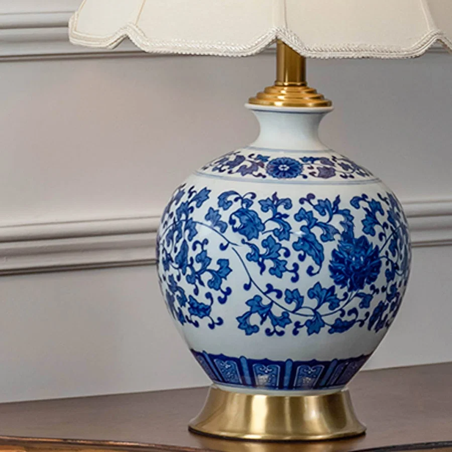 Blue and white ceramic table lamp showcasing floral ceramic craftsmanship with a fabric shade and brass finish.