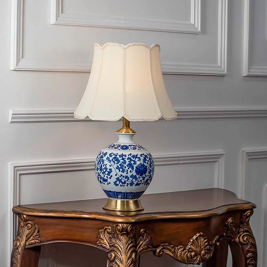 Blue floral ceramic table lamp with fabric shade displayed on a wooden console table offering timeless decor lighting.