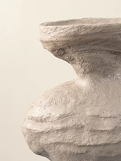 Closeup of beige ceramic vase showing textured sculptural details and artistic organic shape for home styling.