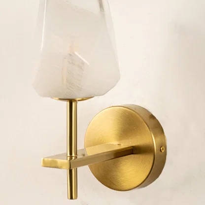 Closeup of white glass and gold metal wall light for modern bedroom and luxury decor styling spaces.

